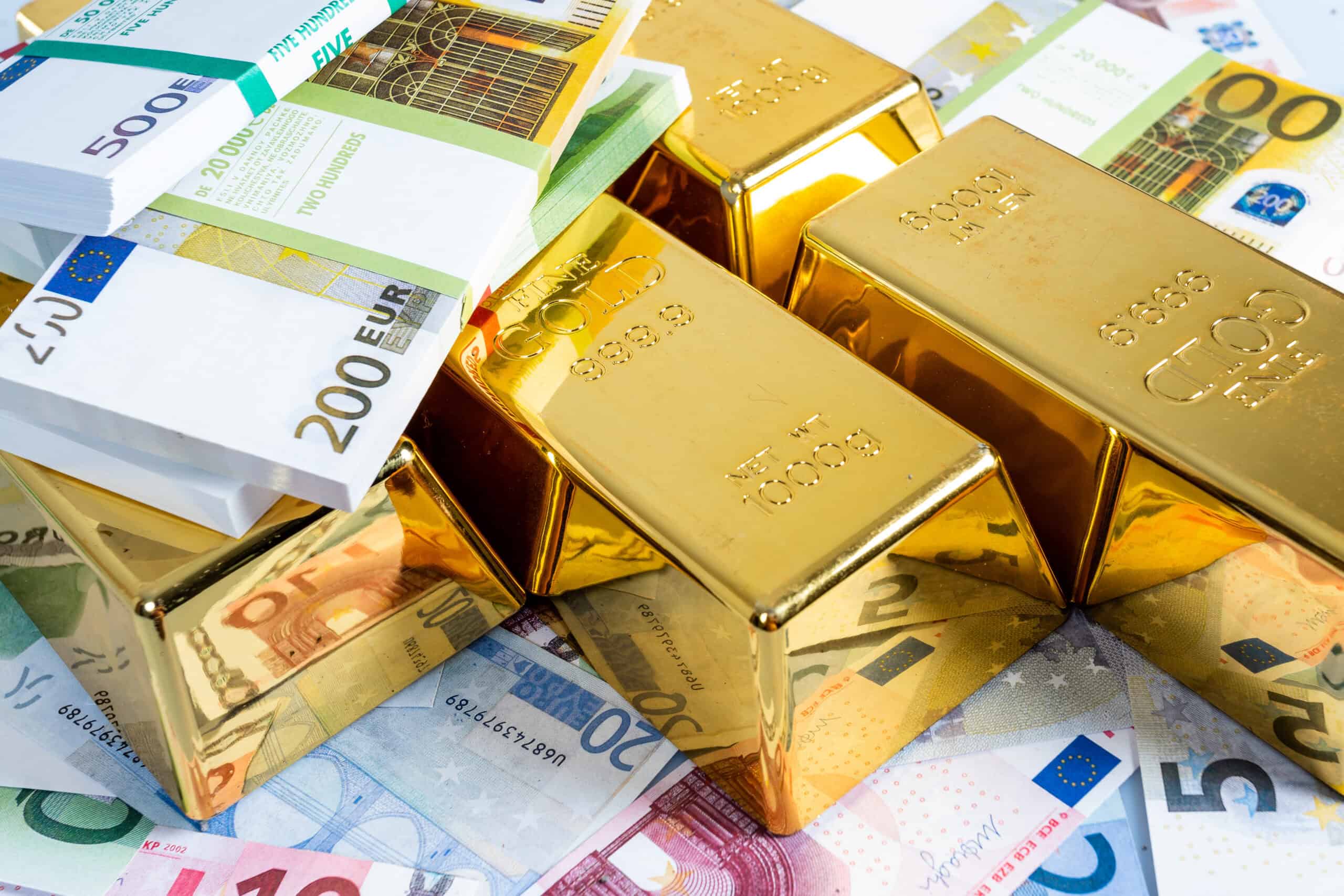 Goldsparplan - Goldbarren und Geld auf einem Haufen